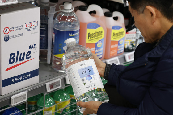 A customer buys bottles of diesel exhaustion fluid made of urea at a supermarket in Seoul on Monday. [NEWS1]