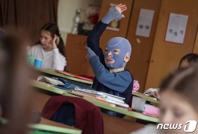 4일(현지시간) 우크라이나 르비우의 한 학교에서 로만(8)이 손을 번쩍 들며 적극적으로 수업에 참여하고 있다. 그는 러시아의 공격으로 몸의 절반 가까이 화상을 입고 30여 차례의 수술을 받았다. 2023.12.04/ ⓒ 로이터=뉴스1 ⓒ News1 권진영 기자