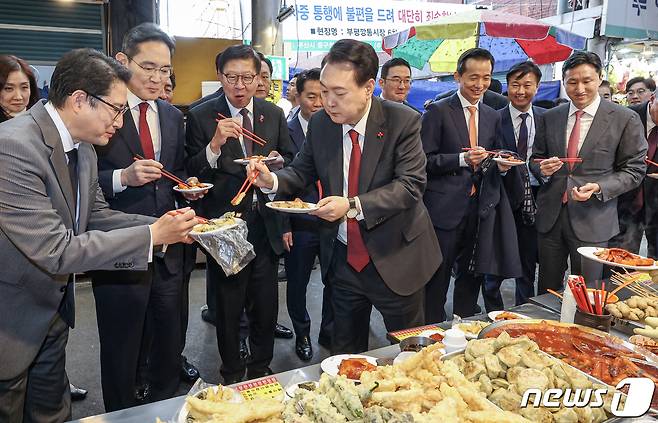 윤석열 대통령이 6일 부산 중구 깡통시장을 방문해 박형준 부산시장과 이재용 삼성전자 회장, 구광모 LG그룹 회장, 조현준 효성그룹 회장, 김동관 한화그룹 부회장, 최재원 SK수석부회장 등 기업총수들과 함께 떡볶이, 튀김, 빈대떡을 맛보고 있다. 2023.12.6/뉴스1 ⓒ News1 부산사진공동취재단