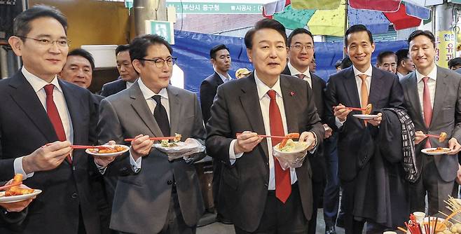 윤석열 대통령이 6일 부산 중구 국제시장을 찾아 기업 총수들과 떡볶이 등을 먹고 있다. 왼쪽부터 이재용 삼성전자 회장, 조현준 효성그룹 회장, 윤 대통령, 구광모 LG그룹 회장, 김동관 한화그룹 부회장, 정기선 HD현대 부회장. /사진공동취재단