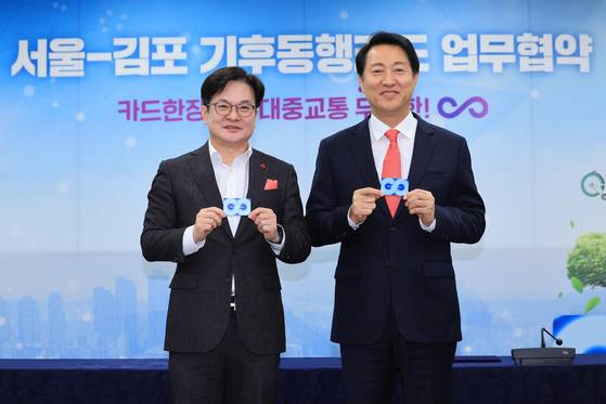 Seoul Mayor Oh Se-hoon, right, and Gimpo Mayor Kim Byung-soo holds up the climate card that allows unlimited access to public transportation including the city bicycle at the Seoul city government office in Seoul on Thursday. [YONHAP]