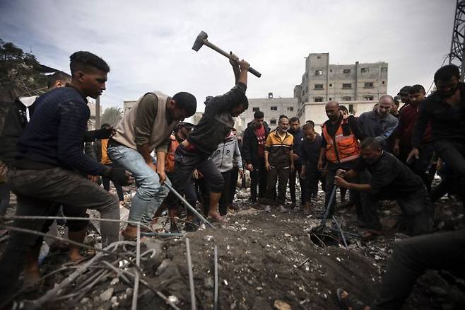 지난 7일(현지시간) 이스라엘의 공습을 받은 가자지구 남부 칸 유니스 난민촌에서 주민들이 생존자를 찾기 위해 콘크리트 건물 잔해를 부수고 있다.[사진출처=AP연합뉴스]