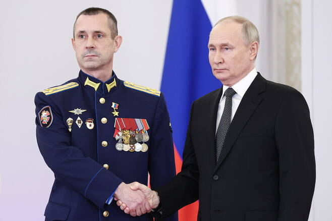 블라디미르 푸틴 러시아 대통령(오른쪽)이 12월9일 ‘조국 영웅의 날’을 앞두고 크렘린궁에서 참전 용사를 치하하고 있다. 타스 연합뉴스
