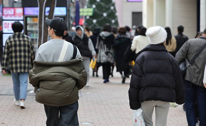 포근한 날씨를 보인 8일 서울 중구 명동거리에서 한 시민이 외투를 반쯤 벗은 채 이동하고 있다. [사진 = 연합뉴스]