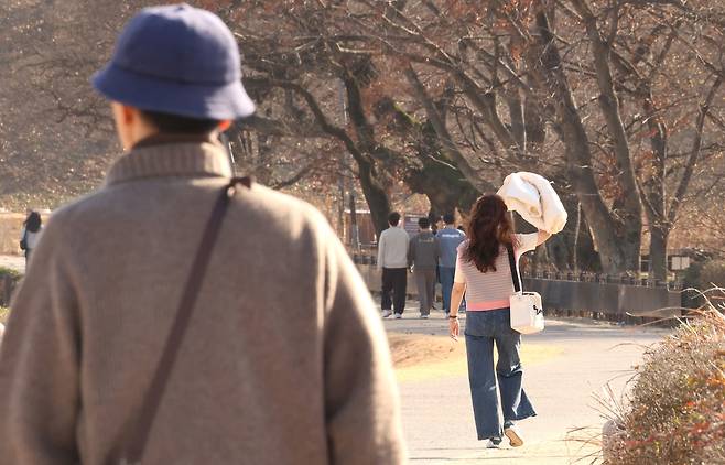 12월의 봄 (경주=연합뉴스) 황수빈 기자 = 8일 오후 경북 경주시 첨성대 일대에서 한 시민이 외투를 벗어 햇빛을 가리고 있다. 2023.12.8 hsb@yna.co.kr