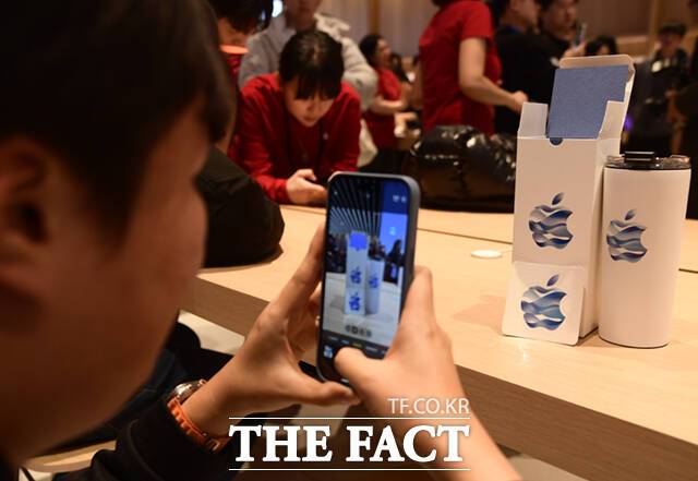 '애플 하남' 매장을 찾은 한 방문객이 자신이 받은 텀블러를 촬영하고 있다. 애플 하남은 한강의 파란색 물결이 들어간 독창적 로고를 선보였다.