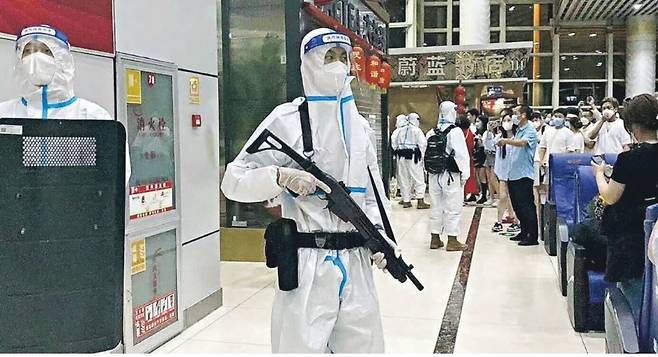 최근 중국 남부 관광지인 윈난성 시솽반나자치주에서 흰 방호복을 입은 경찰이 총을 들고 여행객들을 막는 장면. /중국 인터넷