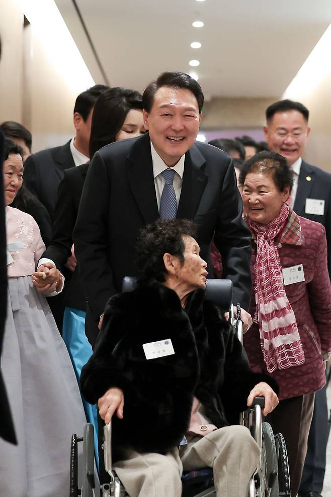 윤석열 대통령이 12일 오후 용산 대통령실에서 칠곡할매글꼴의 주인공 이종희(91) 할머니의 휠체어를 끌고 있다. 칠곡할매글꼴은 경북 칠곡군이 어르신 대상으로 운영하는 성인문예교실에서 한글을 깨친 할머니들의 글씨체로 윤 대통령 부부는 새해 연하장을 할머니의 서체로 제작했다. /대통령실 제공