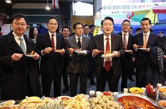 지난 6일 부산 중구 깡통시장에서 윤석열 대통령과 재계 총수들이 떡볶이, 튀김을 먹고 있다. 이들 중 절반 이상은 안경을 착용했다. (오른쪽부터) 김동관 한화그룹 부회장, 구광모 LG그룹 회장, 윤 대통령, 조현준 효성그룹 회장, 이재용 삼성전자 회장, 최재원 SK수석부회장(연합뉴스)