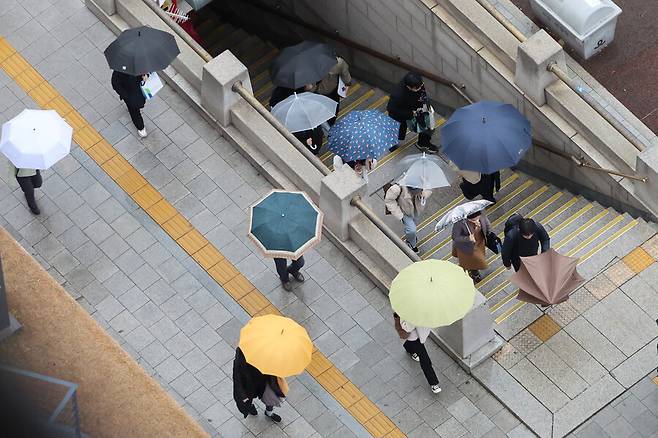 비가 내린 11일 오전 출근길에 오른 시민들이 우산을 쓰고서 서울 중구 시청역 출구에서 나오고 있다. 연합뉴스
