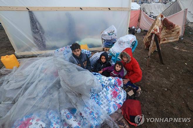 추위에 비닐 끌어 덮은 가자지구 어린이들 (라파 AFP=연합뉴스) 지난 13일(현지시간) 피란민 대부분이 모여 있는 가자지구 남부 라파의 실향민 캠프에서 어린이들이 이불과 비닐을 덮고 야외에 앉아 있다. 이스라엘은 국제사회의 지지가 없더라도 팔레스타인 무장 정파 하마스와 전쟁을 이어가겠다는 입장이다. 2023.12.14 besthope@yna.co.kr