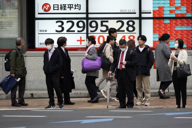 일본 도쿄 시민들이 지난 12일 한 증권사의 닛케이 지수 전광판을 살펴보고 있다. [AP]