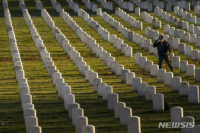 [알링턴 국립묘지=AP/뉴시스] 미국 버지니아주 소재 알링턴 국립묘지에서 12월 16일 묘지를 찾은 한 참배객이 전몰장병의 비석 앞에서 인사를 하고 있다.  알링턴 국립묘지는 이곳에 설치된  남부 연합의 상징물인 여성 동상을 철거하고 대좌만을 남긴 채 다른 역사공원으로 이동시킬 것이라고 이 날 발표했다.  2023.12. 17.