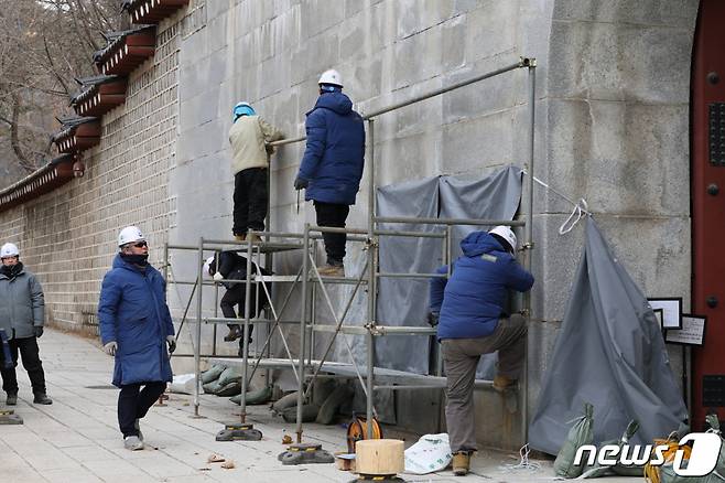 (서울=뉴스1) 박정호 기자 = 경복궁 담벼락 '낙서 테러'가 이틀째 이어진 18일 오전 서울 종로구 통의동 경복궁 영추문 앞에서 문화재청 관계자들이 복구 작업을 위해 가림막 설치 작업을 하고 있다. 2023.12.18/뉴스1  Copyright (C) 뉴스1. All rights reserved. 무단 전재 및 재배포,  AI학습 이용 금지.