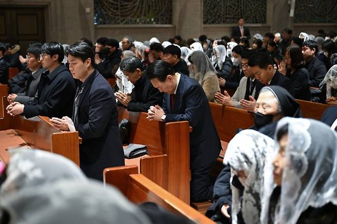 윤석열 대통령이 크리스마스이브인 24일 저녁 서울 종로구 혜화동성당에서 진행된 성탄 대축일 미사에서 기도하고 있다.  [대통령실 제공] 연합뉴스