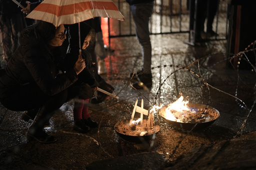 한 여성과 어린이가 23일(현지시간) 베들레헴 구유 광장에서 팔레스타인 가자지구 희생자를 기리기 위한 그리스도 성탄화 앞에 촛불을 밝히고 있다. 베들레헴=AP뉴시스