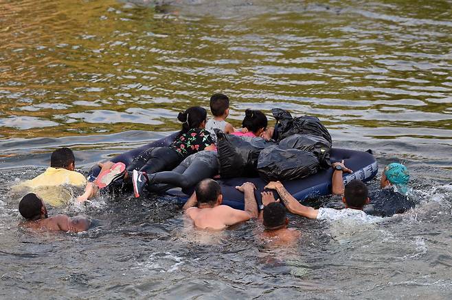 /AFP 연합뉴스 11일(현지 시각) 이민자 가족이 에어매트에 어린이들을 태우고 미국과 멕시코 국경의 리오그란데강을 건너고 있다. 이날 미국 정부가 코로나 팬데믹에 불법 이민자를 즉시 추방하던 ‘42호 정책’을 폐지하자, 국경이 열릴 것으로 기대한 수십만명이 미국 남부 국경으로 몰려들어 혼란이 커지고 있다. 뉴욕타임스에 따르면 미·멕시코 국경에 이주 신청자 약 66만명이 대기했다.이를 관리하기 위해 바이든 행정부는 국경순찰대원과 군인 등 약 3만명을 투입했다.