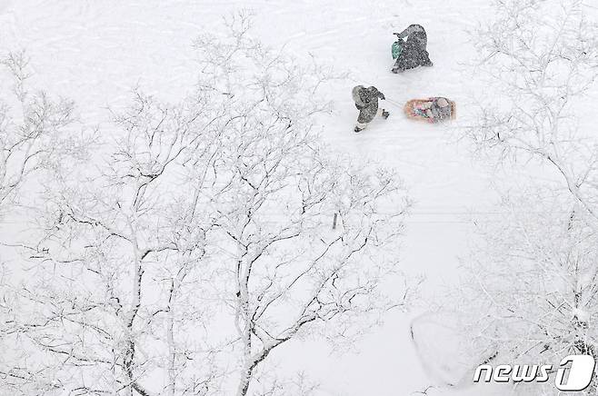 새해를 앞두고 서울과 경기, 강원 일부 지역에 대설주의보가 내린 30일 오후 서울 강동구의 한 아파트단지에서 시민들이 내리는 눈 속에서 산책을 하고 있다. 2023.12.30/뉴스1 ⓒ News1 구윤성 기자