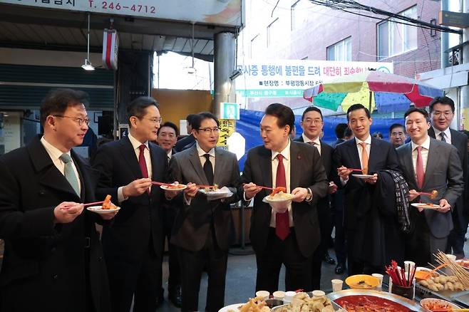 윤석열 대통령이 지난 6일 부산 중구 깡통시장에서 이재용 삼성전자 회장 등 기업 총수들과 떡볶이 등 분식을 시식하고 있다. 왼쪽부터 최재원 SK 수석부회장, 이재용 삼성전자 회장, 조현준 효성그룹 회장, 윤 대통령, 구광모 LG그룹 회장, 김동관 한화그룹 부회장, 정기선 HD현대 부회장, 조원태 한진그룹 회장. 연합뉴스