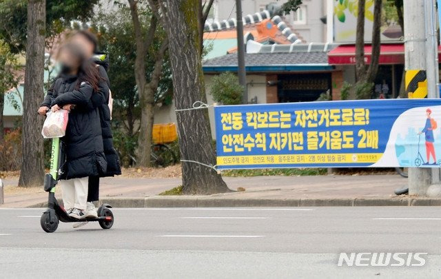 남녀가 안전모를 쓰지 않고, 승차정원도 초과해 전동킥보드를 타고 있다. 뉴시스