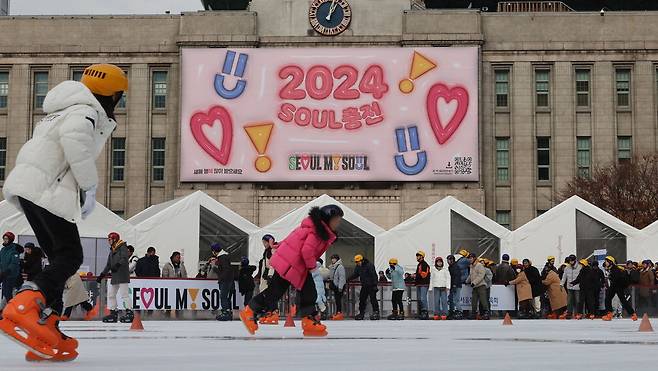 서울시가 2024년 새해를 맞아 서울도서관 외벽 '서울꿈새김판'을 '2024 SOUL 충전'이라는 문구로 새롭게 단장했다. 시는 시민의 마음(SOUL)을 가득 채워드리겠다는 포부를 담았다고 설명했다. 1일 새해 첫날을 맞아 서울도서관 앞 서울광장 스케이트장을 찾은 시민들이 스케이트를 타고 있다.  이승환 기자