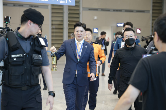 2024 Gangwon Youth Olympics Organizing Committee Cochairperson Jin Jong-oh carries the Olympic flame under police escort out of Incheon International Airport in Incheon on Sunday.  [GANGWON YOUTH OLYMPICS ORGANIZING COMMITTEE]