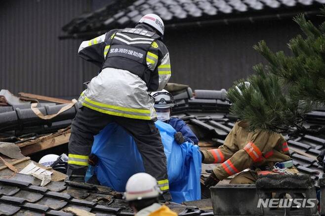 [스즈=AP/뉴시스] 3일 일본 이시카와현 스즈의 소방관과 구조대원들이 지진으로 무너진 집에서 시신을 수습하고 있다. 지난 1일 이시카와현 노토반도에서 발생한 지진으로 지금까지 사망자 숫자는 최소 62명으로 늘어났다. 2024.01.03.