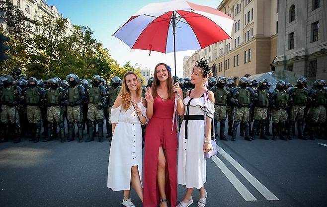 벨라루스에서 국기를 상징하는 흰색과 빨간색으로 된 우산을 쓴 여성들이 시위를 벌이고 있다./트위터