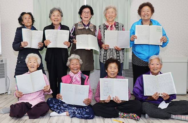 칠곡군문해교실 할머니들이 우크라이나에 보내는 메시지를 쓴 공책을 들고 기념사진을 찍고 있다./경북 칠곡군