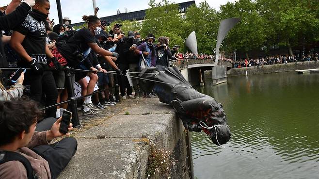 작년 6월 영국 서부도시 브리스틀에서 17세기 사업가 에드워드 콜스턴의 동상을 시위대가 끌어내린 뒤 강물에 빠뜨리고 있다./더타임스