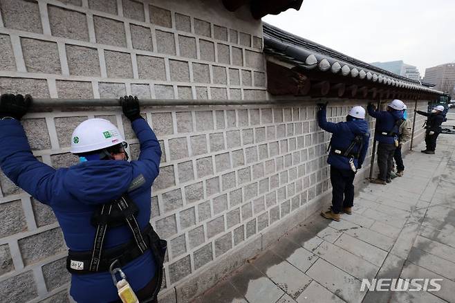 [서울=뉴시스] 조성우 기자 = 문화재청 관계자들이 4일 오전 낙서 복구 작업을 위해 설치됐던 서울 종로구 경복궁 영추문 담벼락 가림막 제거 작업을 하고 있다. 2024.01.04. xconfind@newsis.com