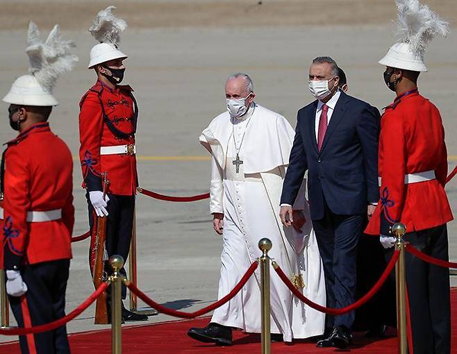 프란치스코(가운데 흰옷 입은 사람) 교황이 5일(현지 시각) 이라크 수도 바그다드 국제공항에 도착해 무스타파 알카디미(교황 오른쪽) 이라크 총리의 영접을 받고 있다. /AP 연합뉴스
