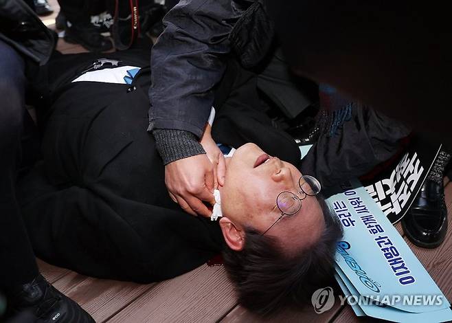 피습 당한 이재명 대표 (부산=연합뉴스) 손형주 기자 = 더불어민주당 이재명 대표가 2일 오전 부산 강서구 가덕신공항 부지를 둘러본 뒤 왼쪽 목 부위 피습을 당해 바닥에 누워 병원 호송을 기다리고 있다. 2024.1.2 handbrother@yna.co.kr(끝)