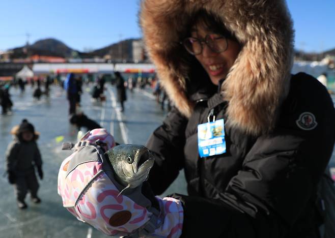 1월 7일 오후 2024 산천어축제장에서 한 참가자가 낚아 올린 산천어를 들어 보이고 있다. / 장련성 기자