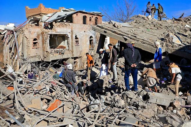 18일(현지 시각) 예멘 반군 후티가 장악하고 있는 예멘 수도 사나에서 주민들이 전날 밤 사우디아라비아 주도 동맹군의 공습으로 파괴된 건물 잔해를 살펴보고 있다. /AFP 연합뉴스