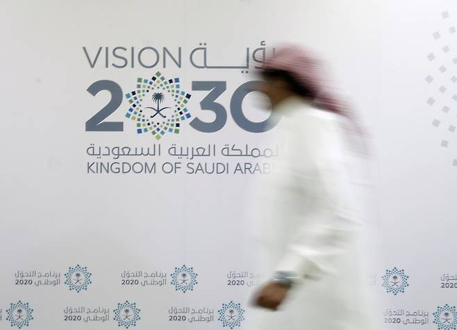 지난 2016년 한 행인이 사우디아라비아 제다에서 진행된 사우디 비전 2030 관련 기자회견장 앞을 지나고 있다. [로이터]
