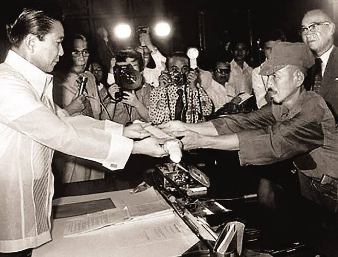 1974년 3월 일본군 ‘최후의 패잔병’ 오노다 히로(오른쪽) 소위가 마르코스 당시 필리핀 대통령에게 군도를 건네며 항복하고 있다. 오노다는 나카노학교 후타마타 분교 출신으로 1944년 12월 게릴라전을 펼치기 위해 필리핀에 왔다. /섬앤섬