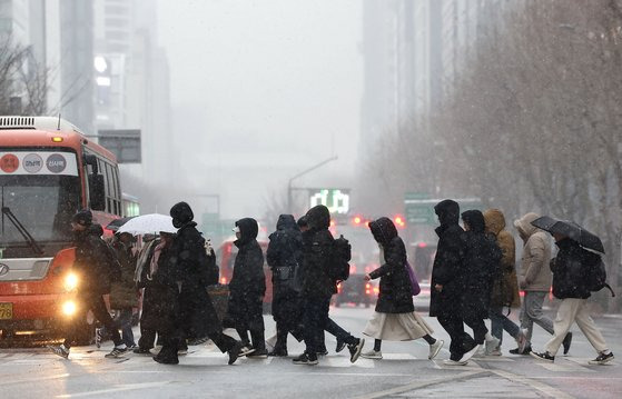 서울 전역에 대설주의보가 발효된 9일 오전 서울 강남역에서 시민들이 눈을 맞으며 걸어가고 있다. 연합뉴스