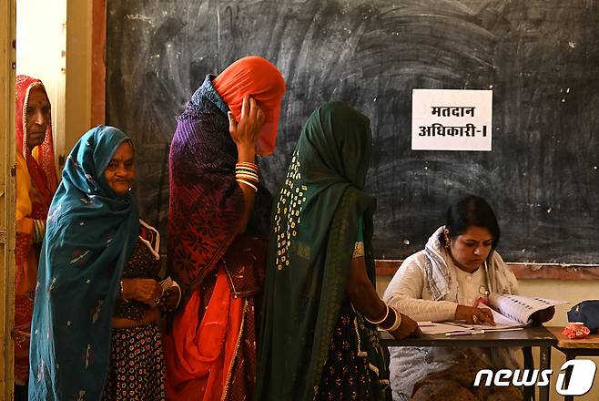 인도 5개주(州)에서 지방선거가 치러진 지난해 11월 서북부 라자스탄주 아지메르에서 여성 유권자들이 투표소에서 투표용지를 교부받는 모습이다. 2023.11.25. ⓒ 로이터=뉴스1 ⓒ News1 김성식 기자