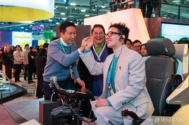 가수 지드래곤이 9일(현지시간) 개막한 세계 최대 가전·정보기기(IT) 전시회 'CES 2024'의 HD현대 부스에서 '엑스에이전트' 기술 시뮬레이터에 탑승해 휠로더 조종 체험을 했다. 정기선 HD현대 부회장은 체험을 마친 지드래곤과 하이파아브를 하고 있다. /사진제공=HD현대