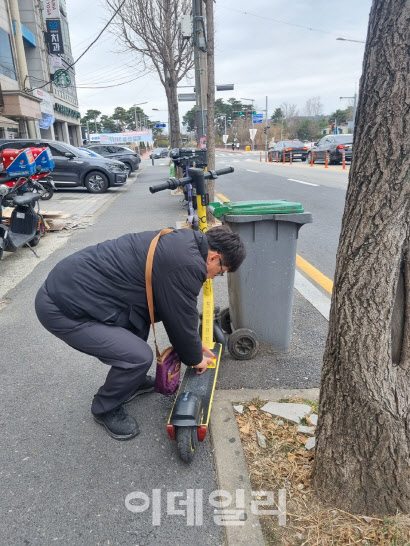 단속 요원이 대전의 한 거리에서 무단 방치된 전동킥보드에 견인을 알리는 예고장을 부착하고 있다. (사진=대전시 제공)