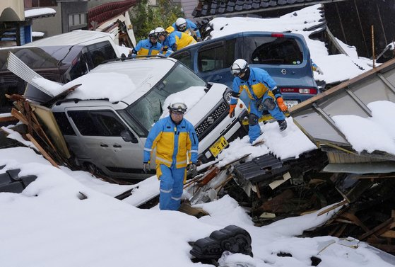 일본 경찰들이 지난 9일 지진해일로 폐허가 된 이시카와현 스즈시의 눈 덮인 주택가에서 실종자들을 찾고 있다. 로이터=연합뉴스