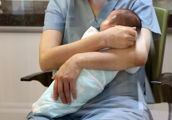 A nursing assistant holds a newborn at a public postpartum care center in Yanggu County, Gangwon, on Dec. 4, 2023. [YONHAP]