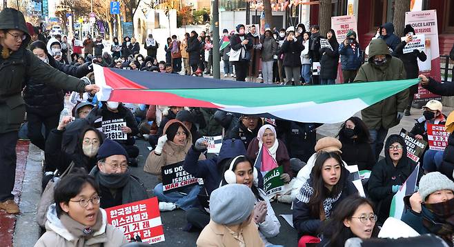 ‘팔레스타인과 연대하는 한국 시민사회 긴급행동’이 2024년 1월7일 주한 이스라엘대사관이 있는 서울 종로구 서린동 청계한국빌딩 맞은편에서 연 집회에서 국내에 거주하거나 여행 중인 외국인들이 시민들과 함께 대형 팔레스타인 국기를 머리 위로 넘기며 ‘프리 팔레스타인\'을 외치고 있다.