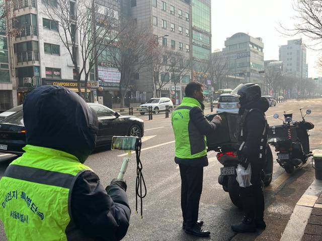 지난 10일 오전 서울 마포구 망원동 도로에서 서울시청 소속 단속반이 오토바이 배달 기사에게 공회전 제한 규정을 설명하고 있다. 권정현 기자