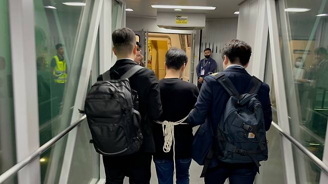 필리핀에서 검거된 피의자 A씨(가운데)가 17일 인천국제공항행 비행기에 오르고 있다. [경찰청 제공]