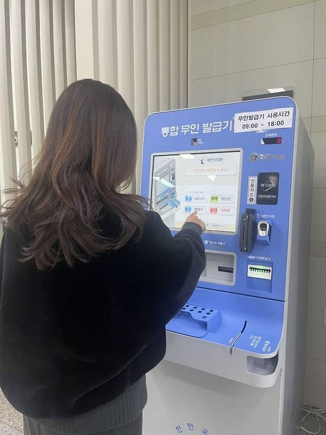 기장군 민원실에 설치된 대법원통합무인발급기에서 민원서류를 발급하고 있는 민원인.
