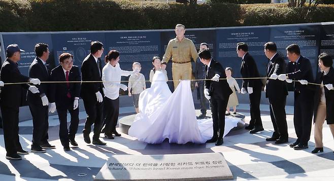 전쟁고아들과 함께… 소박한 위트컴 장군 동상 - 11일 부산 평화공원에서 열린 위트컴 장군 기념 조형물 제막식에서 참석자들이 흰색 천을 걷어내 다섯 전쟁고아와 함께 걸어가는 장군의 모습을 공개하고 있다. 뒤편 비석 앞·뒷면에는 장군의 업적과 조형물 건립에 동참한 시민들의 이름을 새겼다. /뉴시스