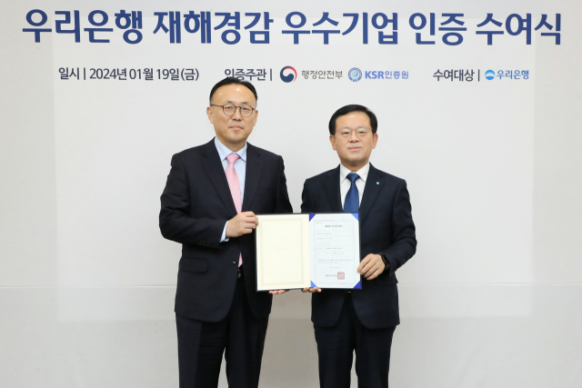 우리은행이 은행권 중 처음으로 행정안전부가 주관하는 ‘재해경감 우수기업’ 인증을 취득했다. 조병규(오른쪽) 우리은행장과 이한경 행정안전부 재난안전관리본부장이 19일 서울 중구 우리은행 본점에서 열린 수여식에서 기념촬영을 하고 있다./사진 제공=우리은행