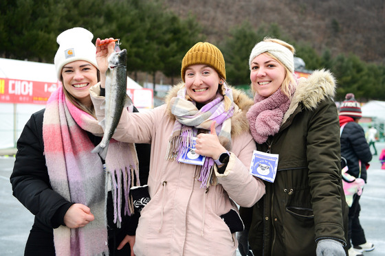 International visitors to the Hwacheon Sancheoneo Ice Festival pose with a trout during the festival in Hwacheon, Gangwon, on Jan. 20. [YONHAP]